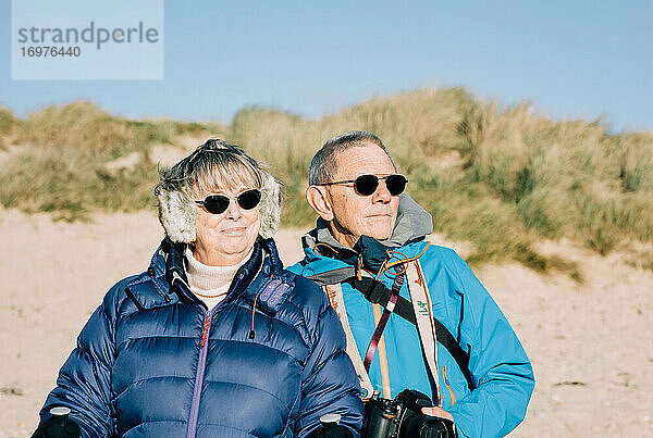 Ein Paar in den 70ern stand am Strand und schaute auf das Meer hinaus