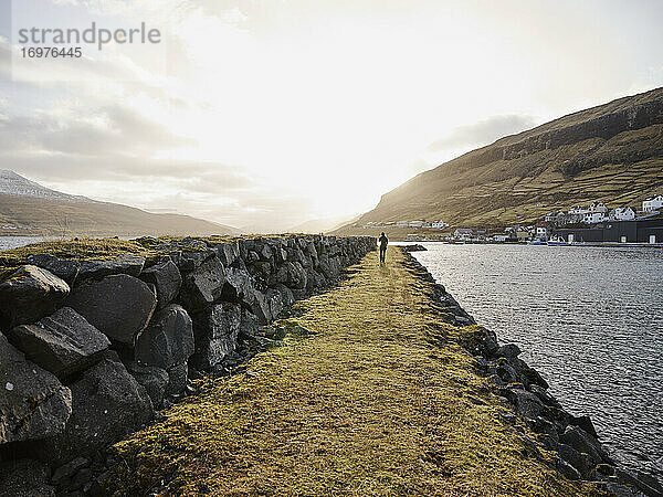 Frau  die in Haldarsvík auf den Färöer-Inseln am Steg entlanggeht