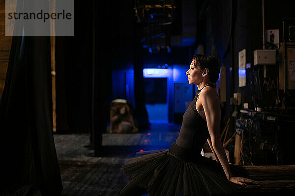 Erwachsene Ballerina sitzend hinter der Bühne