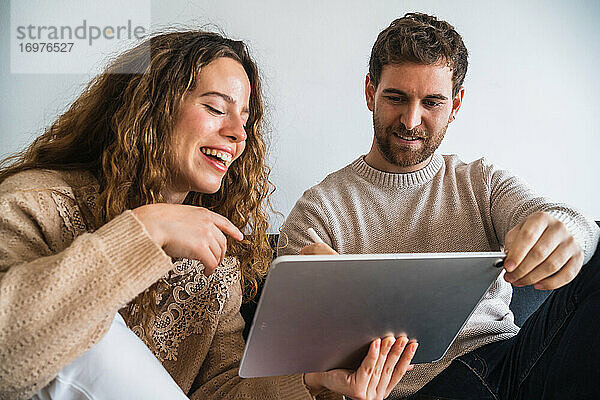 Vergnügtes Paar  das gemeinsam am Tablet zeichnet