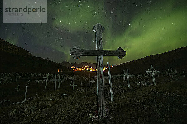 Nordlicht - Aurora Borealis leuchten am Himmel über den Holzkreuzen des Friedhofs von Tasiilaq  Grönland