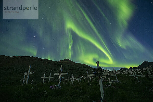 Nordlicht - Aurora Borealis leuchten am Himmel über den Holzkreuzen des Friedhofs von Tasiilaq  Grönland