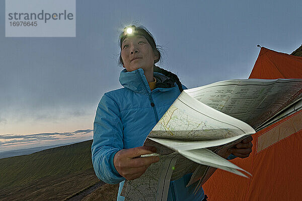 Wanderin beim Lesen der Wanderkarte am Pen Y Fan in Wales bei Sonnenaufgang
