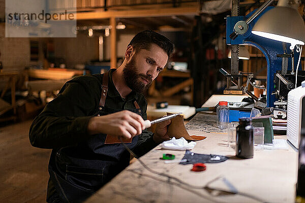 Fokussierter Handwerker mit Pyrographiemaschine auf Leder