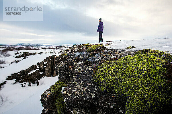 Stehende Person mit Felsen und Moos im Thingvellir-Nationalpark