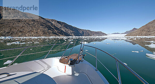 kleines Motorboot  das durch einen Eisberg auf einem Fjord in Grönland fährt