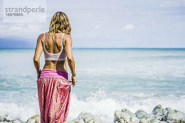 Schöne Frau in Yogahose schaut auf das Meer hinaus