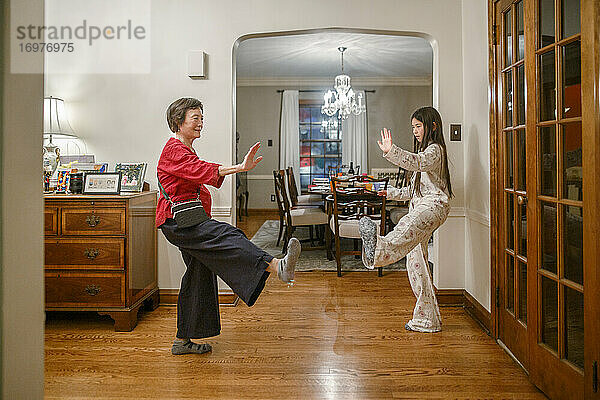 Eine Großmutter bringt ihrer kleinen Enkelin zu Hause Tai Chi bei