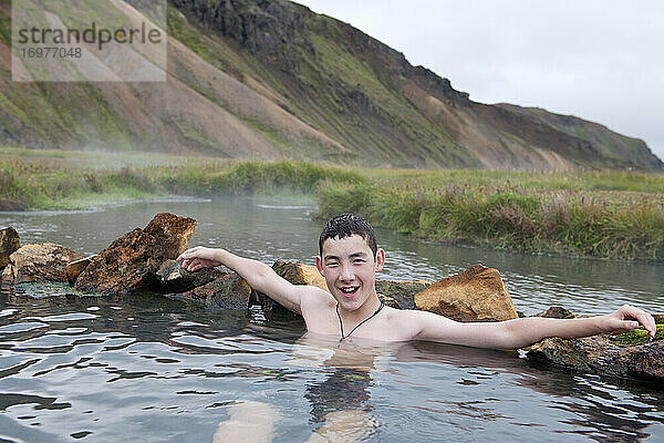 Jugendlicher  der ein Bad in einer geothermischen Quelle in Island genießt