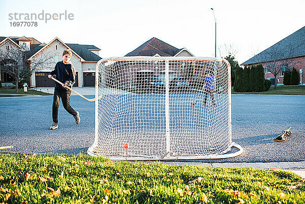 Zwei Jungen spielen Streethockey in einer Wohnstraße im Herbst.