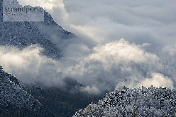 Wolken zwischen Bergen in einer verschneiten Landschaft im Winter