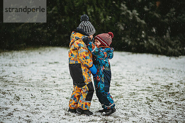 Kinder umarmen draußen an einem verschneiten Tag im Winter im Hinterhof