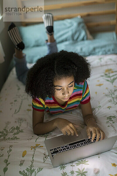 Draufsicht auf ein zehnjähriges gemischtrassiges Mädchen bei der Arbeit am Laptop