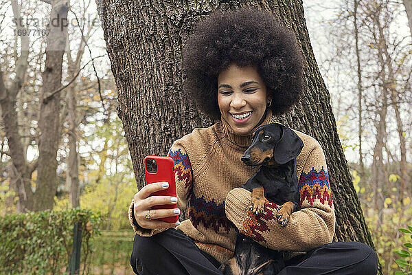 ein kubanisches Mädchen macht ein Selfie mit ihrem Dackel im Park