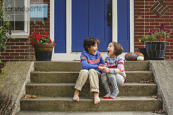 Ein kleiner Junge und ein Mädchen sitzen auf der Treppe und schreien vor Freude laut auf
