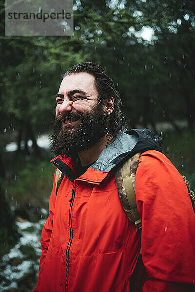 Bärtiger Mann in der Natur an einem verschneiten Tag lächelt glücklich
