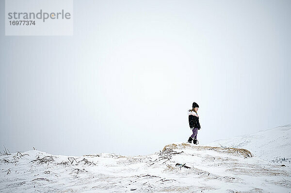 Unerkanntes Kind in warmer Kleidung auf verschneitem Berghang