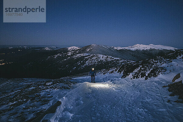 Junger Mann auf Schneeschuhen drängt zum Sonnenaufgang vor schneebedeckten Berggipfeln zum Gipfel  Guadarrama  Madrid