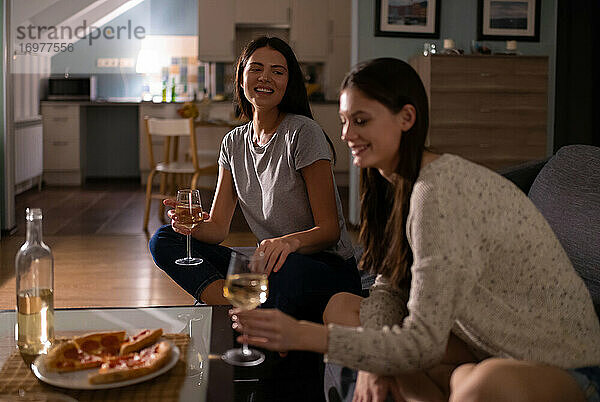 Glückliche Frauen kommunizieren während einer Weinparty auf der Couch