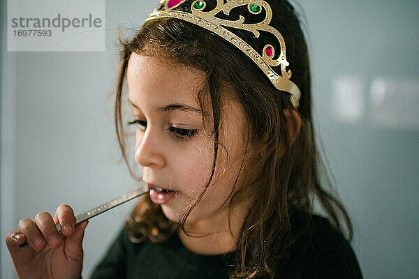 4 Jahre altes Mädchen trägt ein Diadem und isst aus einem Messlöffel
