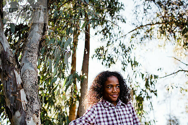 Junger Junge  der neben einem Baum im Park in Chula Vista steht
