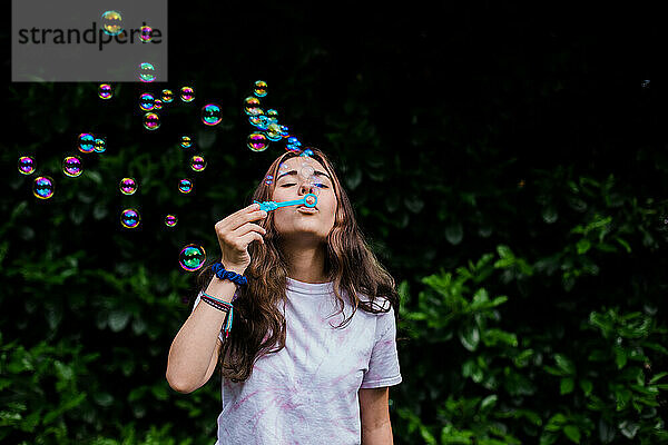 Teenager bläst Seifenblasen im Freien mit schillernden Farben und Aktivität