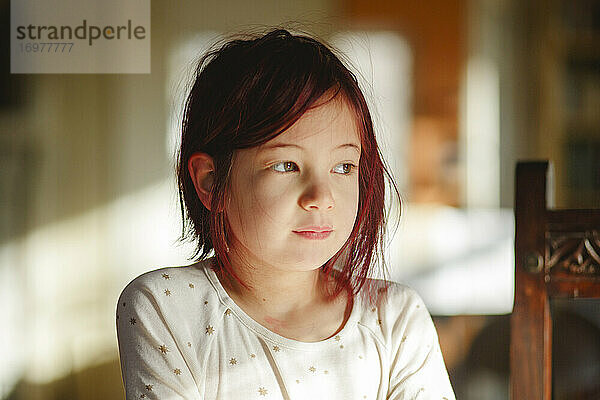 Porträt eines kleinen Kindes mit gefärbten roten Haaren  das in schönem Licht sitzt
