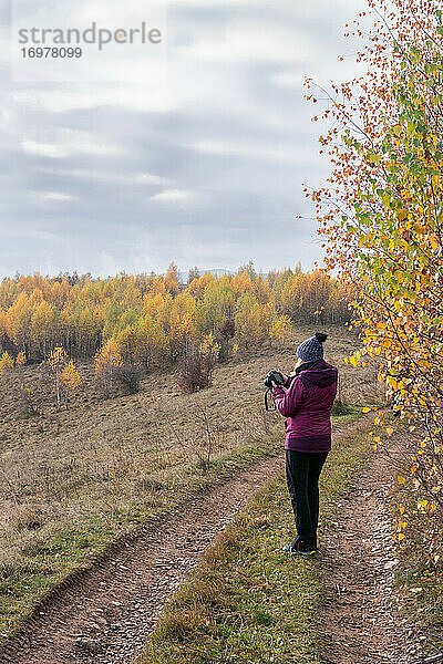 Frau fotografiert Bäume mit gelben Blättern  Herbst auf dem Hügel