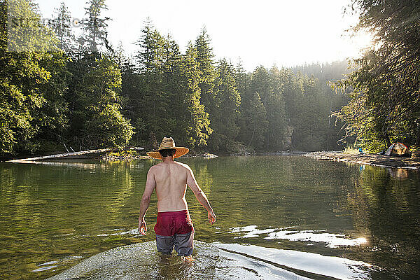 Ein junger Mann watet im Ohanapecosh River in Washington.