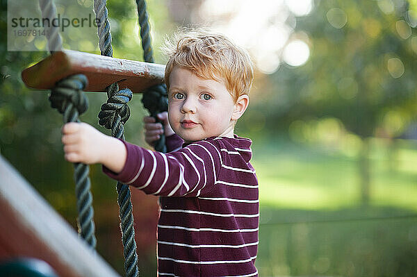 Close up von Jungen 3-4 Jahre alt Klettern Leiter auf playlet im Hinterhof