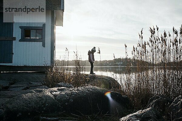 ein junges Mädchen stand auf den Felsen neben einer traditionellen schwedischen Hütte