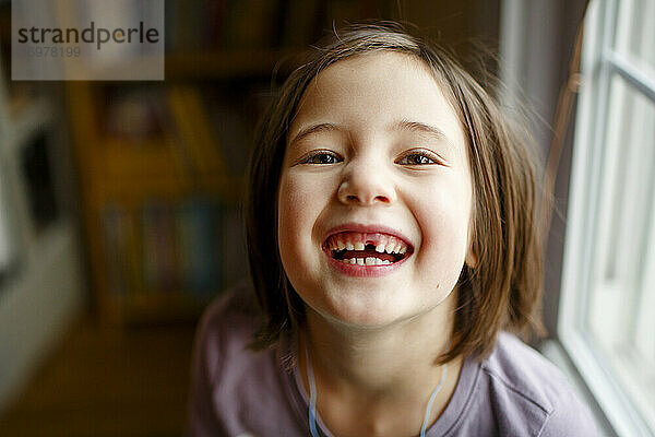 Ein bezauberndes Mädchen mit strahlenden Augen zeigt stolz einen fehlenden Zahn