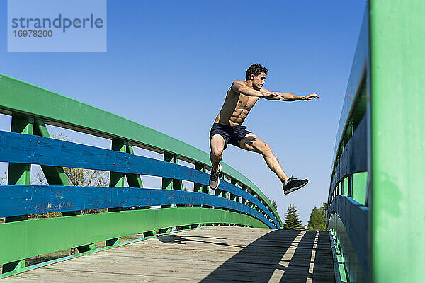 Mann springt beim Training über eine Brücke