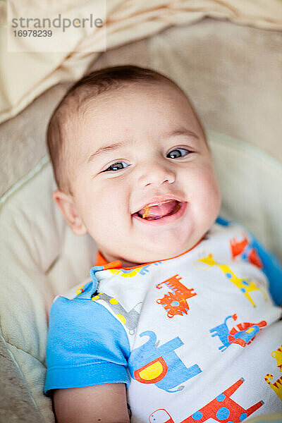 Lächelndes Baby isst seine erste feste Mahlzeit