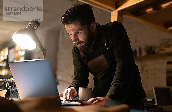 Handwerker mit Laptop auf dem Tisch in der Werkstatt