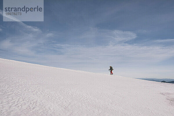 Junger Mann wandert bergauf auf Eis Schnee gegen blauen Himmel  Gredos  Spanien