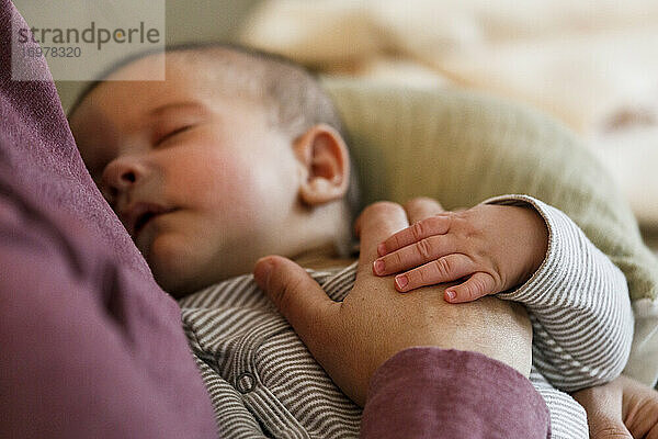 Ein kleiner Junge schläft auf dem Schoß seiner Mutter  während sie ihre Hand auf seinen Bauch legt