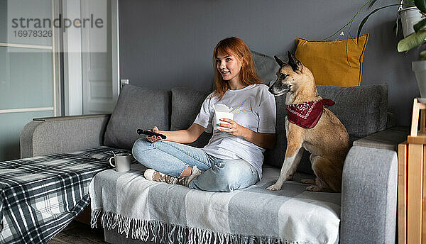 Fröhliche Frau mit Hund vor dem Fernseher