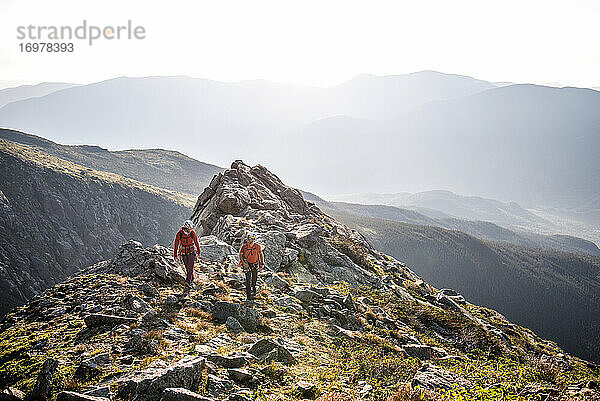 Mann und Frau wandern am Morgen auf einem Bergrücken in den Bergen