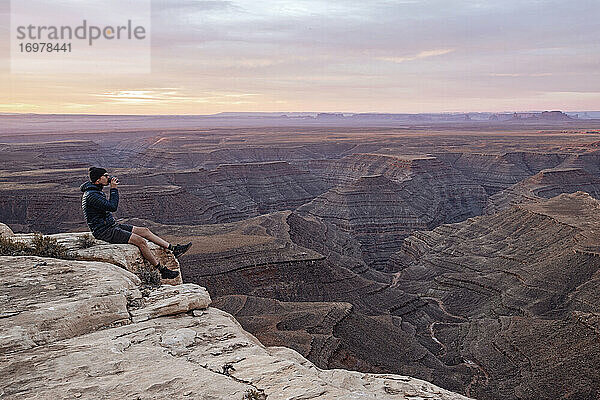 Mann trinkt Kaffee am Rande einer Klippe sitzend  Mexican Hat  Utah
