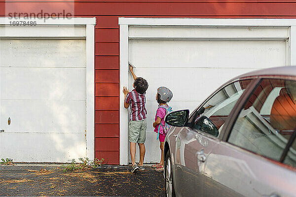 Zwei kleine Kinder stehen zusammen und drücken die Tastatur  um die Garage zu betreten