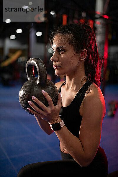 Starke Frau beim Training mit der Kettlebell in einem modernen Fitnessstudio