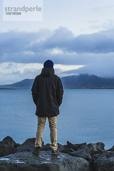 Mann steht am Meer in Reykjavik