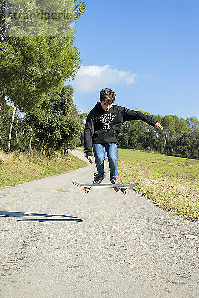 Action Shot eines jungen Skater Teenager männlich springen hoch auf einem Hügel Straße