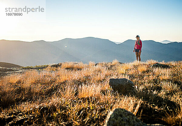 Trailrunnerin bei Sonnenaufgang in den Bergen stehend