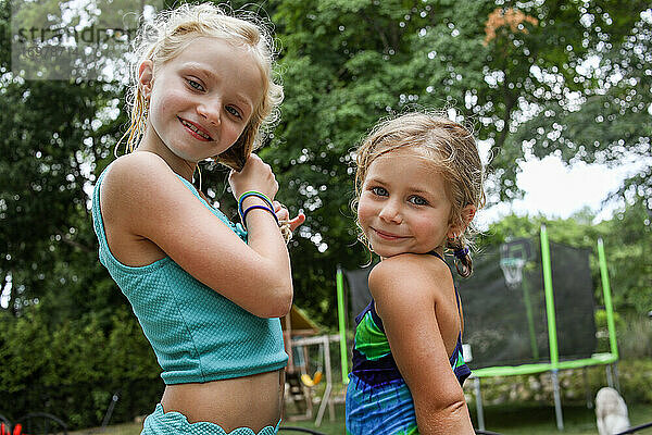 Porträt von zwei Mädchen  die im Sommer im Hinterhof zusammen stehen