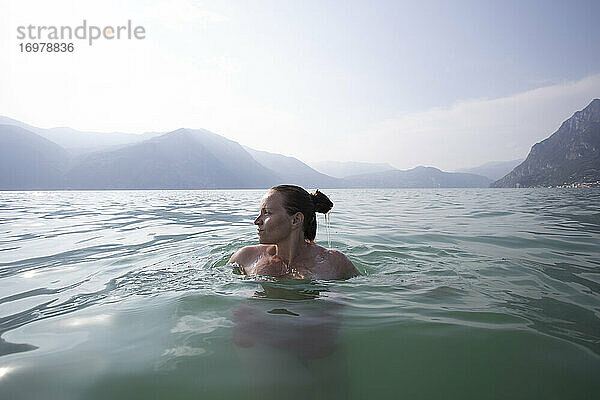 Eine Frau  die in der Mitte eines Sees in Italien schwimmt