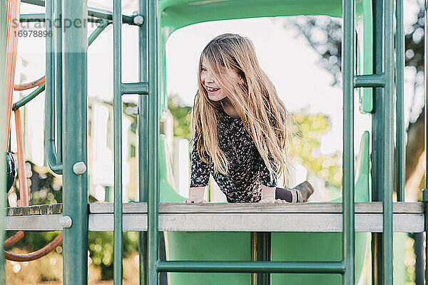 Junges lächelndes Mädchen spielt auf dem Spielplatz