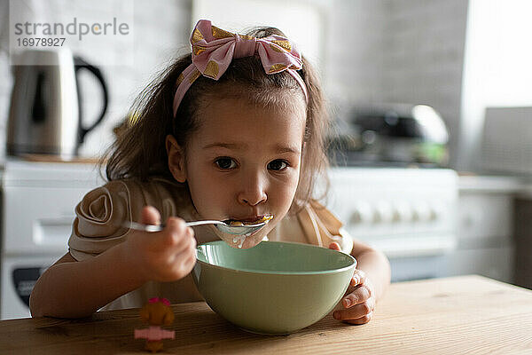 Kleines Mädchen isst Müsli zum Frühstück