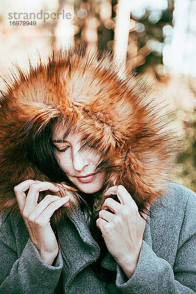 Glückliche Frau im Wald mit ihrem Wintermantel